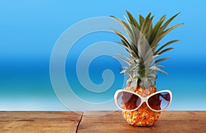 Pineapple with sunglasses on the table. Beach and tropical theme.