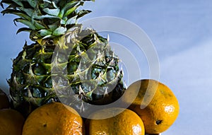 Pineapple and tangerines on a white plate close-up.