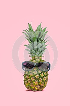 Pineapple wearing sunglasses on pink background. Minimal summer concept.