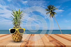 Pineapple on wooden table in a tropical landscape, Fashion hipster pineapple, Bright summer color, Tropical fruit with sunglasses photo