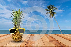 Pineapple on wooden table in a tropical landscape, Fashion hipster pineapple, Bright summer color, Tropical fruit with sunglasses