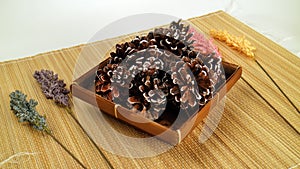 Pinecones in a basket on brown paddy stalk mat with four flowers