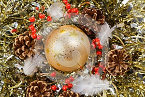 Pines cones, feather, red berries and golden Christmas ball on a