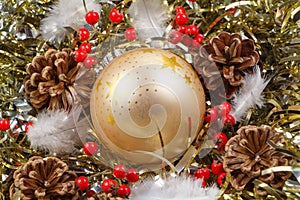 Pines cones, feather, red berries and golden Christmas ball on a