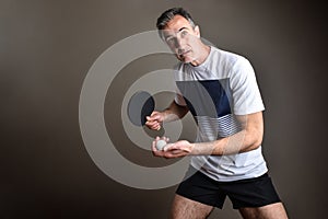 Ping-pong player ready to make a serve on gray background