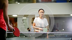 Ping pong playing. Young smiling woman playing table tennis. The woman misses the ball and goes to pick it up