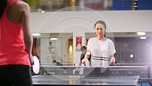 Ping pong playing. Young woman playing table tennis with her friend