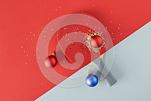 Ping pong racket with christmas tree balls and sequins on pastel red and blue background, top view.