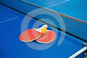 Pingpong rackets and ball and net on blue pingpong table