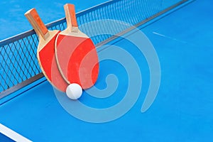 Pingpong rackets and ball and net on blue pingpong table