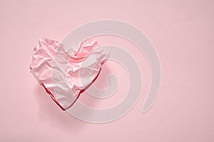 Pink abstract background with crumpled paper heart. Crumpled paper in the shape of a heart on a pink background. Valentine card, d