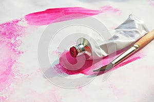 Pink and acrylic paints tubes and hand drawn abstract magenta watercolour drawing picture on white textured paper background