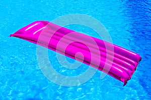 Pink air mattress floating on water of swimming pool