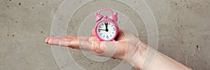 Pink alarm clock in female hands. Time is in our hands. Time concept