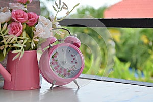Pink alarm clock and rose flower
