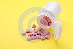 Pink antidepressants with different emoticons on yellow background