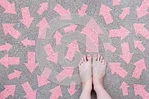 Pink Arrow Choice Concept. Female Bare Feet with Pink Nail Polish Manicure Standing and Many Direction Arrows Choices on the Road