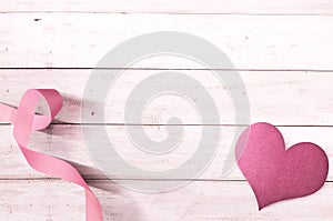 Pink awareness ribbon and heart on a wooden background