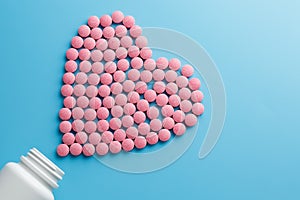 Pink B12 pills in the shape of a heart on a blue background, poured out of a white can