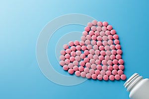 Pink B12 pills in the shape of a heart on a blue background, poured out of a white can