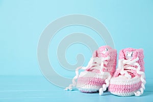 Pink baby booties on blue background with copy space
