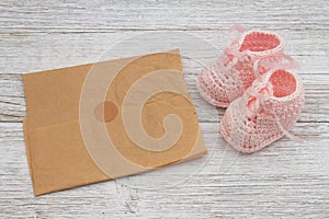 Pink baby booties with paper on weathered wood photo