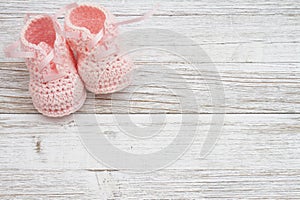 Pink baby booties on weathered wood