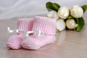 Pink baby booties on wooden surface