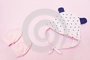 pink baby coif and mittens. Clothes for little girl on pink background top view