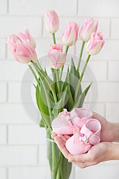 Pink baby`s bootees and pink tulips