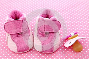 Pink baby shoes and dummy