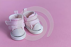 Pink baby shoes on a gentle pink background. The concept of the first steps, birthday, expectation, pregnancy, motherhood,