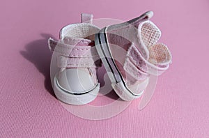 Pink baby shoes on a gentle pink background. The concept of the first steps, birthday, expectation, pregnancy, motherhood,