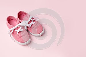 Pink baby shoes on pink background, concept of first steps, birthday, expectation, pregnancy, maternity, motherhood, parenthood.