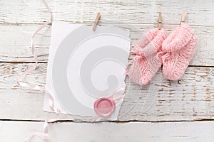 Pink baby's booties. Small girls sock and blank card with wax seal on white wooden background