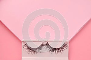 Pink background with false lashes copy space