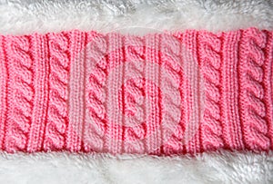 Pink background of hand-knitted pattern on the spokes-pigtail