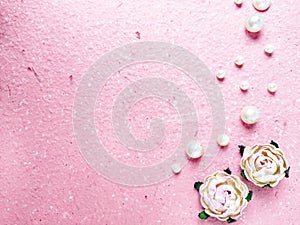 Pink background with pearls and roses. Top view with copy space