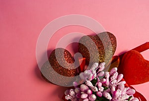 Pink background. St. Valentine`s Day. Red hearts in spangles with bows. Love. Bouquet of flowers. The place for an inscription.