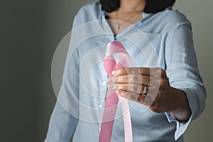 Pink badge ribbon on woman hand to support breast cancer cause. breast cancer awareness concept