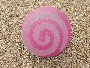 Pink ball or sphere in brown mulch