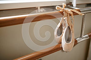 Pink ballet shoe hanging on barre, nobody