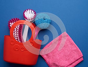 Pink basket with washing sponges, brushes on a blue background