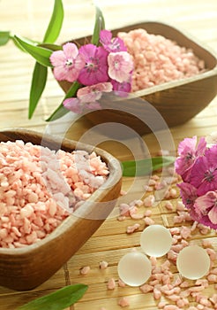 Pink bath salts in wooden bowls and flowers.