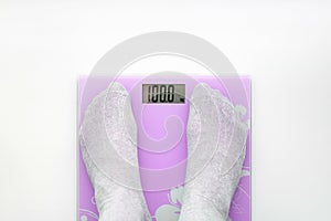 Pink bathroom scales.A man weighs himself on a bathroom scales.Display shows ninety nine kilos.View from above.