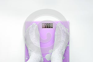 Pink bathroom scales.A man weighs himself on a bathroom scales.Display shows ninety nine kilos.View from above.