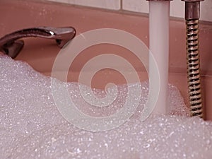 Pink Bathtub Filled to the Brim: Metallic Tap Flows with Water and Abundant Foam