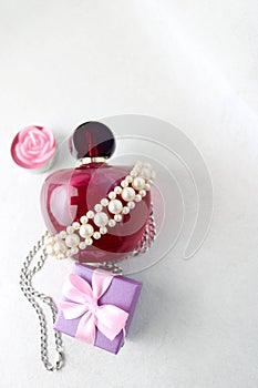 Pink beautiful glass transparent bottle of female perfume decorated with white pearls and a candle in the form of a rose blue smal