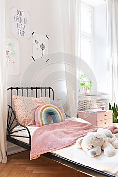 Pink bedding and teddy bear on small kids bed