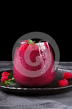 Pink berry smoothie in a glass topped with raspberry and mint